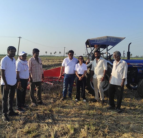 Kisani team members with farmers beside a tractor and baler in a harvested field